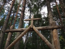 Entrance to the cemetery. Towering cross. Wooden gate with a cross to the Christian Orthodox rural cemetery, Orzega village Karelia, Russia. Pine forest. Sky with clouds. Religious theme