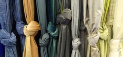 Curtain and fabric for drapery and interior decoration. Samples of fabrics in the store are hung vertically and tied in knots. Curtains in yellow, blue, green, white tones. Curtains in the showcase