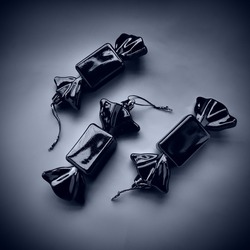 Christmas decorations sweets. Three wrapped candies. Beautiful unusual decorations for the New Year and Christmas. Black and white monochrome photo with blue tone. Ropes for  Christmas tree