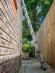 Aluminium tubular section telescopic access ladder fully extended  leaning against a wall