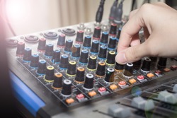 Recording engineer’s hand adjusts volume on audio sound board, Turning a dial on a mixing board