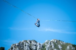 Highliner against blue sky walking slackline tightrope hanging in the mountains