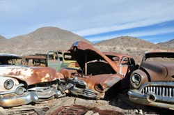 Rusty old cars near mountains and desert in national park Death Valley