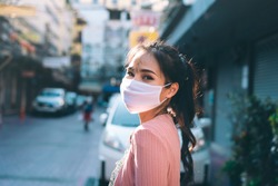 Social distance and new normal lifestyle virus protect at outdoor area concept. Happy asian adult woman tan skin wear mask on face. Background chinatown landmark destination. Bangkok, Thailand.
