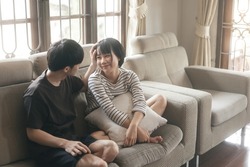 Young adult asian lover couple together living at home concept. Happy smile people sitting on sofa cozy style indoor on day. Background with window light.