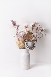 Beautiful dried flower arrangement in a stylish ceramic white vase. Dried flowers include pink proteas, banksia, gold palm leaf, kangaroo paw, cotton and ruscus leaves.