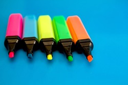 Bright colored markers for highlighting text on a blue background, colored felt-tip pens for drawing.