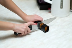 woman sharpening a knife with a special knife sharpener, close up