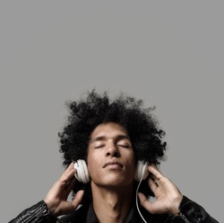 Retro man with afro listening to music on DJ headphones with eyes closed. isolated on grey background in studio.