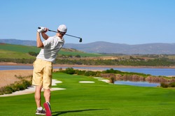 golfer hitting golf shot with club on summer vacation