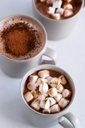Mugs of hot chocolate cocoa drink, comforting cozy delicious milky mocha topped with roasted toasted marshmallows