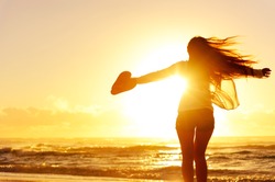 carefree woman dancing in the sunset on the beach. vacation vitality healthy living concept
