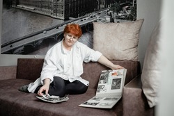 grandmother sits on the couch and looks at photos of her youth, nostalgic for the old days, the city of Kemerovo February 25, 2021