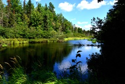 The headwaters of the Wisconsin River by Land O Lakes, Wisconsin with deep blue reflective water and clouded sky.