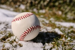 Baseball ball on green grass with snow. Baseball Match Day. Regular season games. Baseball league, team competition and championship. Baseball bat and ball. Sport party in United States. Professional