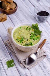 Green cream soup with peas and sesame seeds in a ceramic bowl on a wooden background. Selective focus.