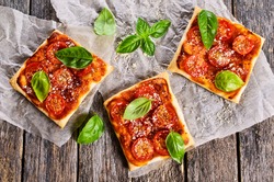 Pie with tomatoes, cheese and Basil on parchment paper.