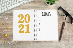 New Year goals List 2021 with notebook written in handwriting about plan listing of new year goals and resolutions setting. flat lay style. Christmas planning concept.