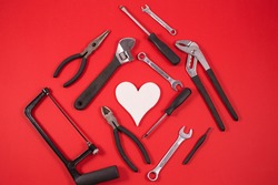 Construction tools for repairs and whire Heart on a red background. DIY tools, Various carpentry. Top view with space for text. Valentines Day concept.