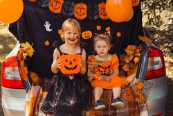 Children celebrating Halloween in trunk of car.