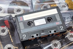 One audio cassette tape lying on a pile of audio cassettes lying on top of each other