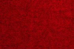 red cotton terry towel lies on a flat surface close-up