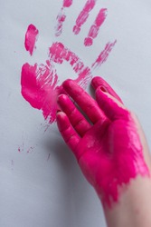 Pink handprint  and painted hand on grey paper