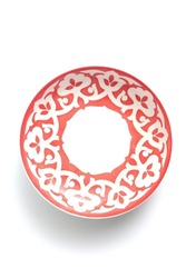 A red plate for food decorated with white national ornaments on a white background