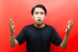 asian man questioning why with upset, shock and confuse expression isolated over red background. 
