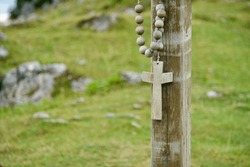 Old religious sign on graveyard on tree in nature. Wooden cross. Symbolism of christian worship, spirituality, mourning, grief, sorrow and sadness. Tranquil holy background. Pray in cemetery. Christ.