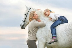 Mother teaching daughter to ride a horse.