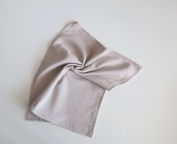 wrinkled beige light grey fabric tissue on white table. crumple rolled rag tissue spirall