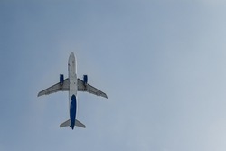A passenger jet taking off and silhouetted against the blue sky. The plane is flying with passengers on a journey.