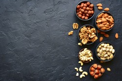 Assortment of nuts on  a black slate or stone background - healthy snack.Top view with copy space.