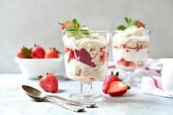 Eton mess - traditional english dessert with meringue, whipped cream and fresh berries in a glasses on a light slate, stone or concrete background. 
