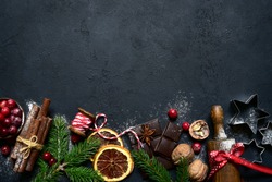 Christmas baking background with ingredients for making cake or biscuit on a black slate, stone or concrete table. Top view with copy space.
