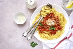 Spaghetti bolognese in a white plate on a light concrete,stone or slate background.Top view.