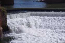 Awesome fall of water on the River Tarn, at the causeway where the strong current passes the weir of Albi, in France, producing white foam and powerful turbulences
