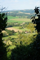Verdant, hilly countryside landscape with agricultural fields, seen from above from the ramparts of Cordes-sur-Ciel, a rural town in the region of Albi (Tarn Department), in the South of France
