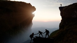 Male hiker celebrating success on top of a mountain in a majestic sunrise and Climbing group friends helping hike up .Teamwork , Helps ,Success, winner and Leadership concept .