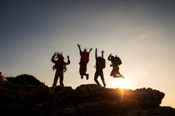 Climbing group friends jumping on top mountain and amazing sunset sky .Teamwork , Helps ,Success, winner and Leadership concept .