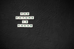 Word The Future Is Vegan with rough black backdrop. Top view sign with copy space. Vegan Activism.
