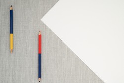 Top view of empty white paper near two sharpened colored pencils lie on grey background. Flat lay. No people. Copy space. Artistic tools, drawing, creativity, design, creativity and object concept