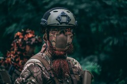 Portrait of a bearded military soldier with an air-soft face guard and a helmet. Portrait of a soldier outside. 