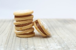 small sweet appetizer with white flour and white delicacy alfajor limeño on a wooden base and rustic white background