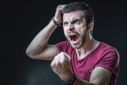 Enraged furious young man screaming in anger, pulling his hair out