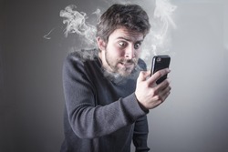 Angry man shouting at his cell phone, enraged with the bad service, burning with rage
