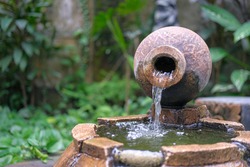 front view of Indonesia traditional clay pot or vase or vas or also called kendi as water fountain on a pond.