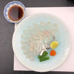 A plate of Fugu (Puffer fish). Thinly sliced. Served with lime, momijioroshi and Ponsu sauce. Taken at Shimonoseki city, Japan.