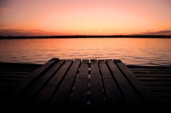  orange sunset  on a lake and wooden pier